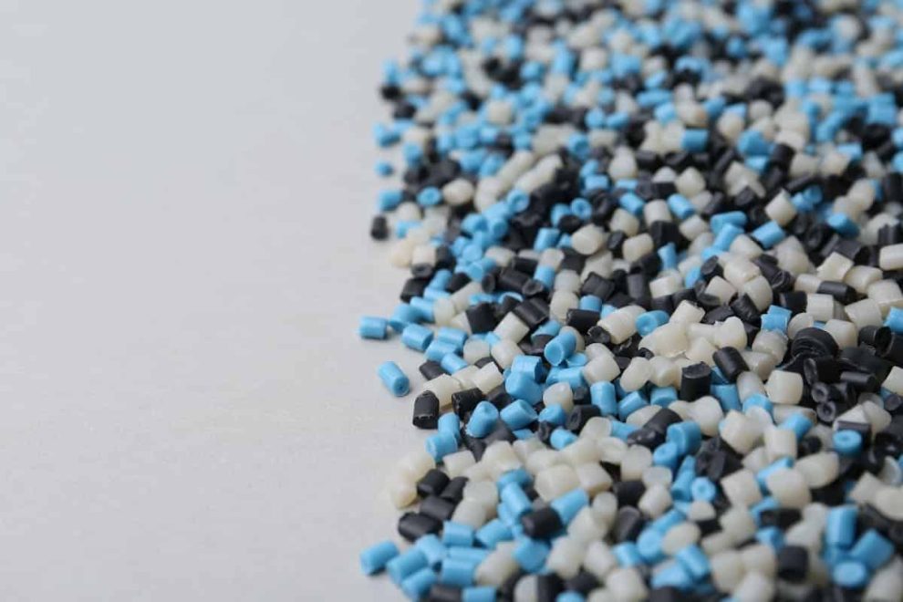 Elastómeros termoplásticos - Pila de gránulos de plástico de colores sobre fondo gris, primer plano.