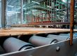 Recubrimiento de rodillos industriales en una línea de producción de una fábrica de pisos de madera.